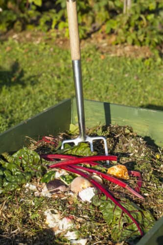 garden fork sitting in a pile of compost and organic waste