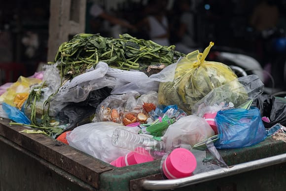 Mixed wastes are thrown in a trashgarbage such as vegetables, plastic bags, bottles, and fruits at street market.